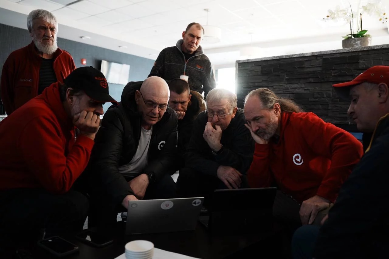 A group of people gather around a laptop
